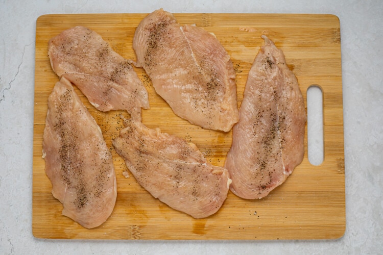 Seasoned chicken breasts on wooden cutting board