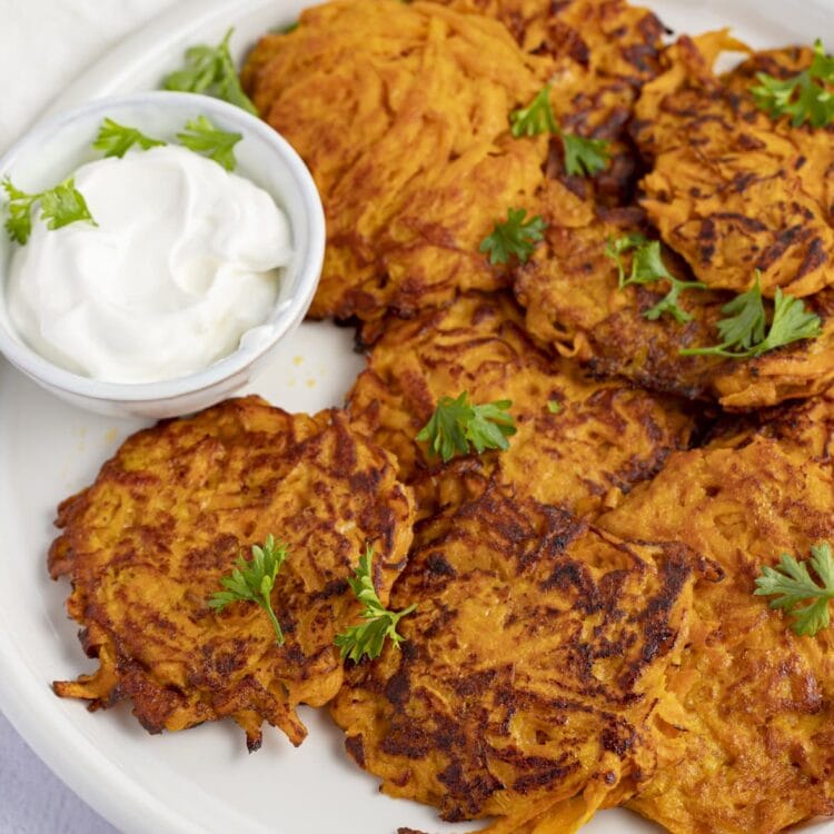 Sweet potato hash browns on a white plate next to sour cream