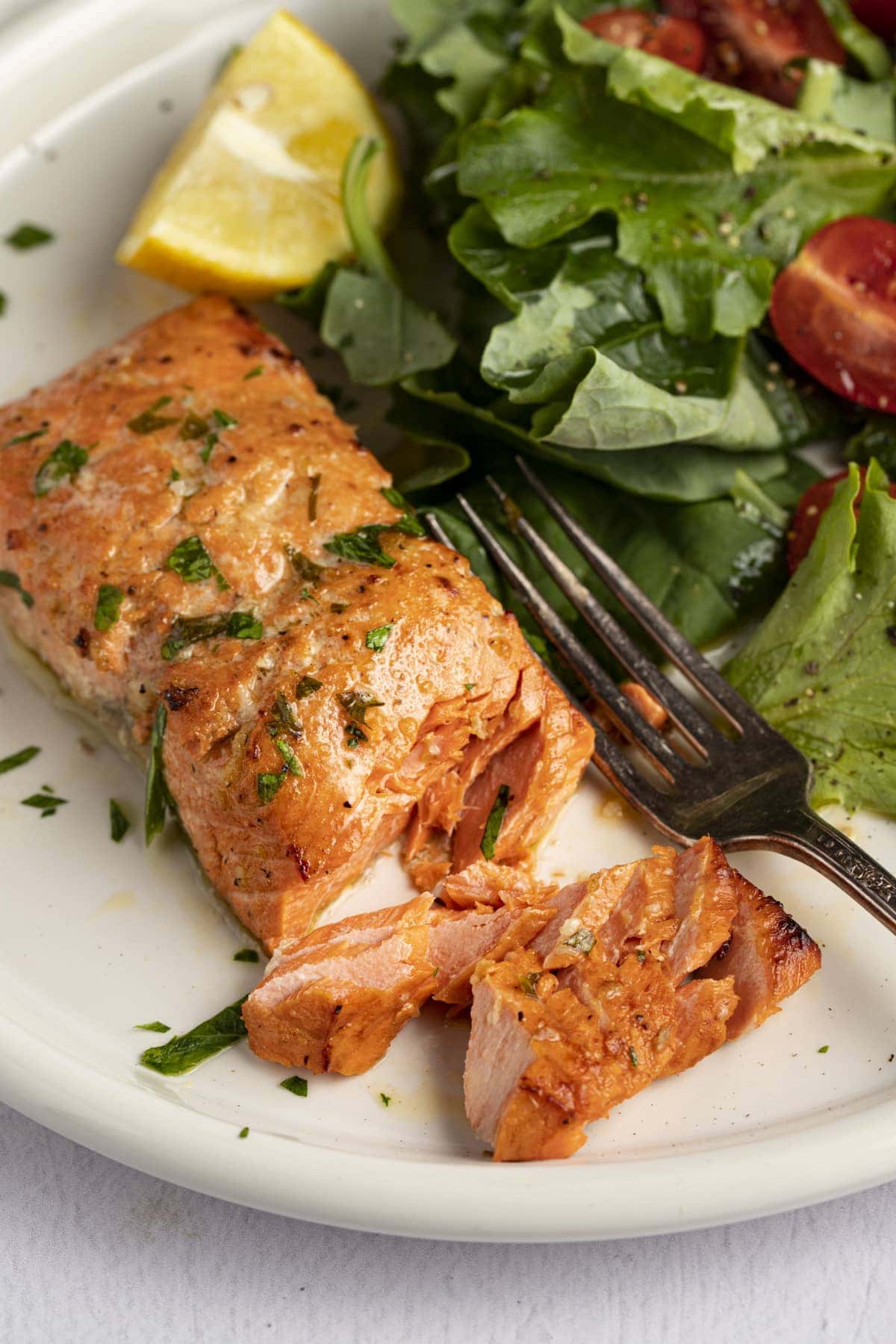 Broiled salmon on a plate next to a small salad