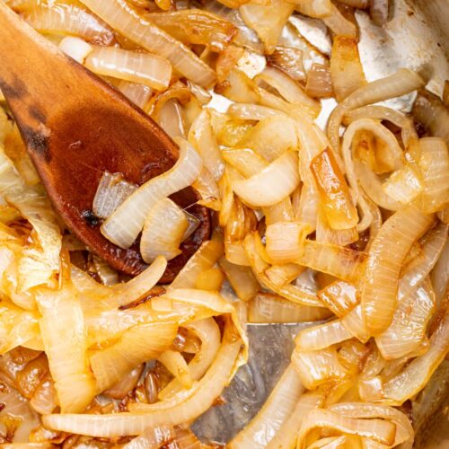 sauteed onions in a skillet with a wooden spoon