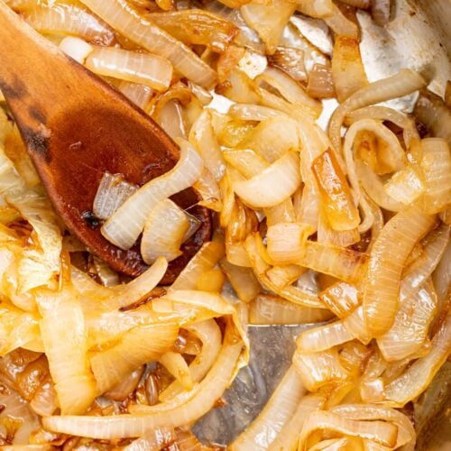 sauteed onions in a skillet with a wooden spoon