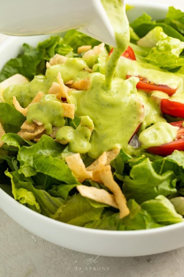 Avocado dressing poured over a salad in a bowl