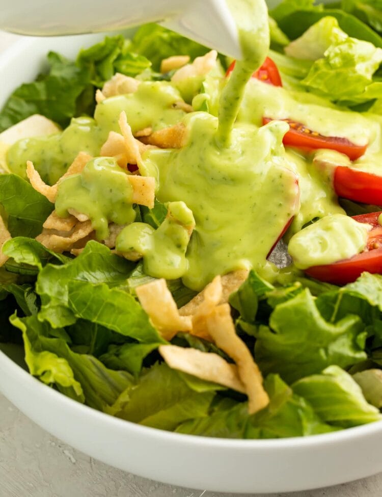Avocado dressing poured over a salad in a bowl