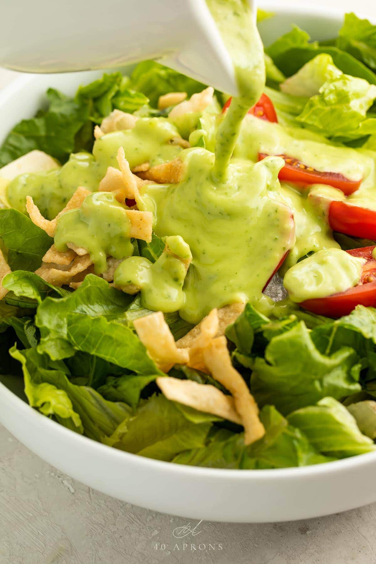 Avocado dressing poured over a salad in a bowl