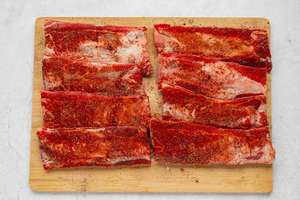 Seasoned beef back ribs lined up on a cutting board.