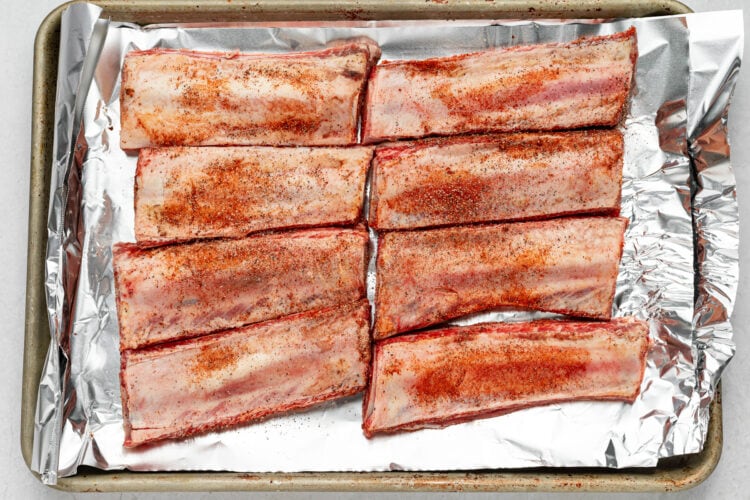 Seasoned beef back ribs on a sheet pan lined with aluminum foil.