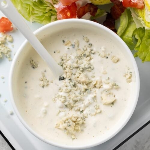 Blue cheese dressing in a small bowl next to salad