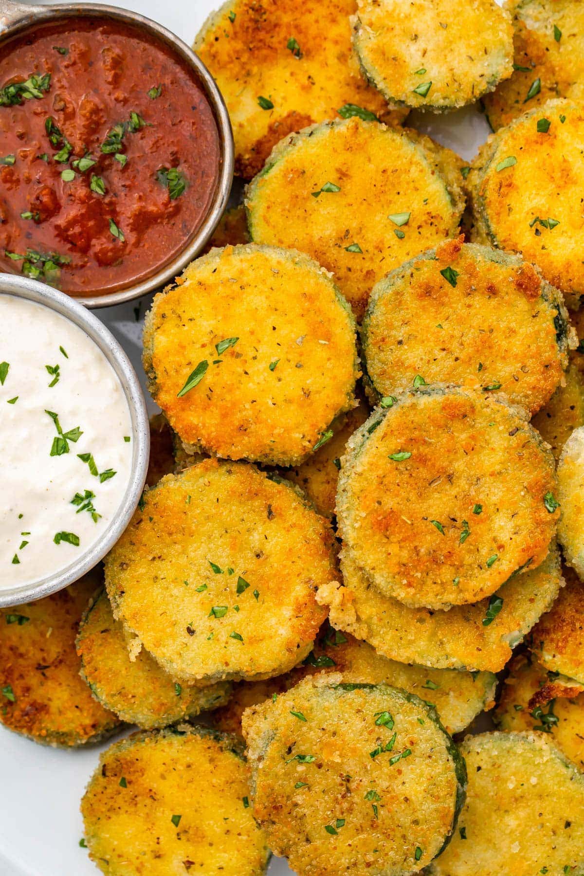 Fried zucchini next to small cups of marinara and parmesan ranch