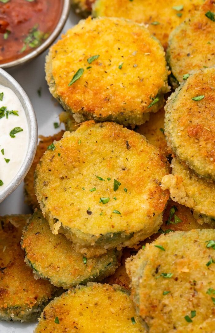 Crispy fried zucchini next to a creamy parmesan dipping sauce