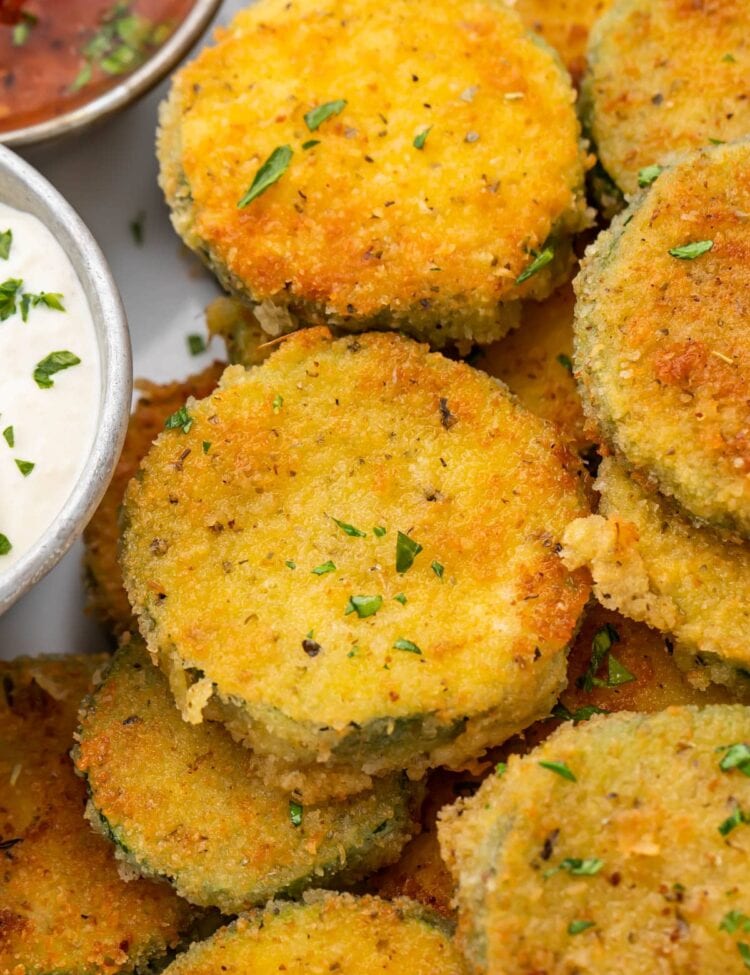 Crispy fried zucchini next to a creamy parmesan dipping sauce