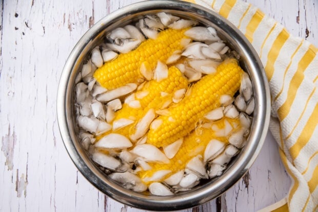 Ears of corn in ice bath in large bowl