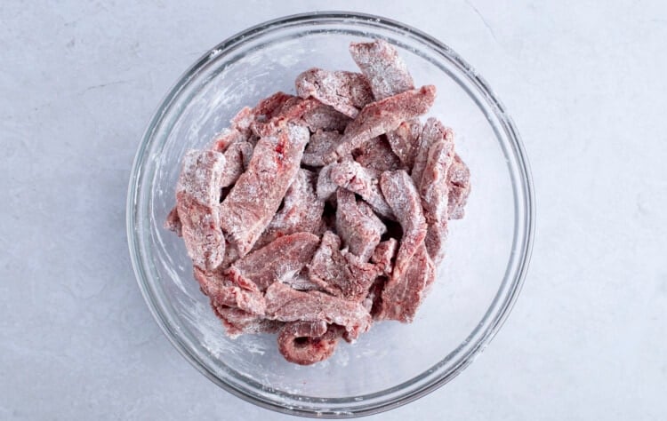 Beef and cornstarch in large glass mixing bowl