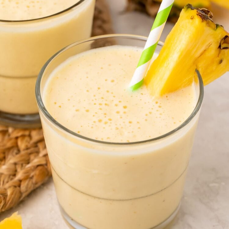 Short glasses of pineapple smoothie with a pineapple wedge garnish