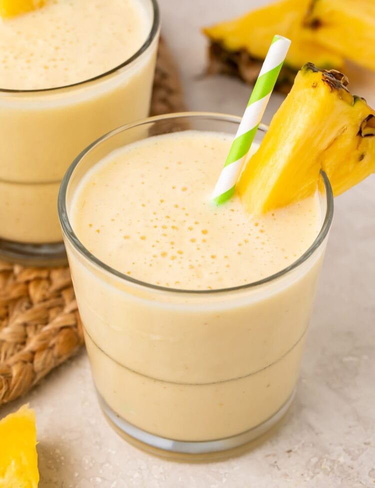 Short glasses of pineapple smoothie with a pineapple wedge garnish