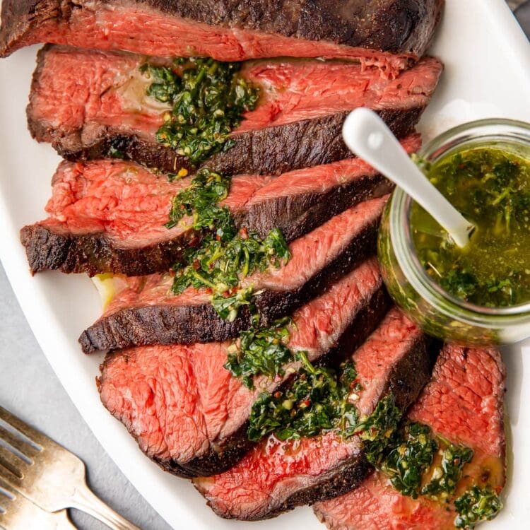 Sliced sous vide tri tip on a platter with chimichurri