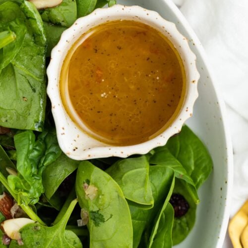 hot bacon dressing in a small dish next to salad