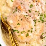 Pork chops and rice in a casserole dish with gold spoons