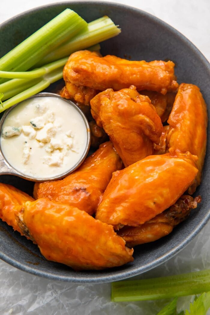 Air fryer chicken wings and celery on a platter with blue cheese dressing