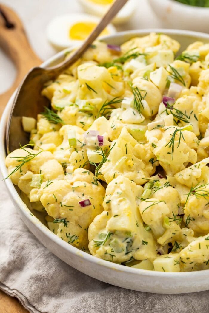 Cauliflower potato salad in a large bowl with a spoon