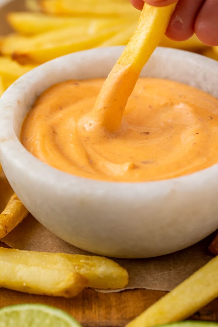 A french fry dipped into a small bowl of chipotle mayo