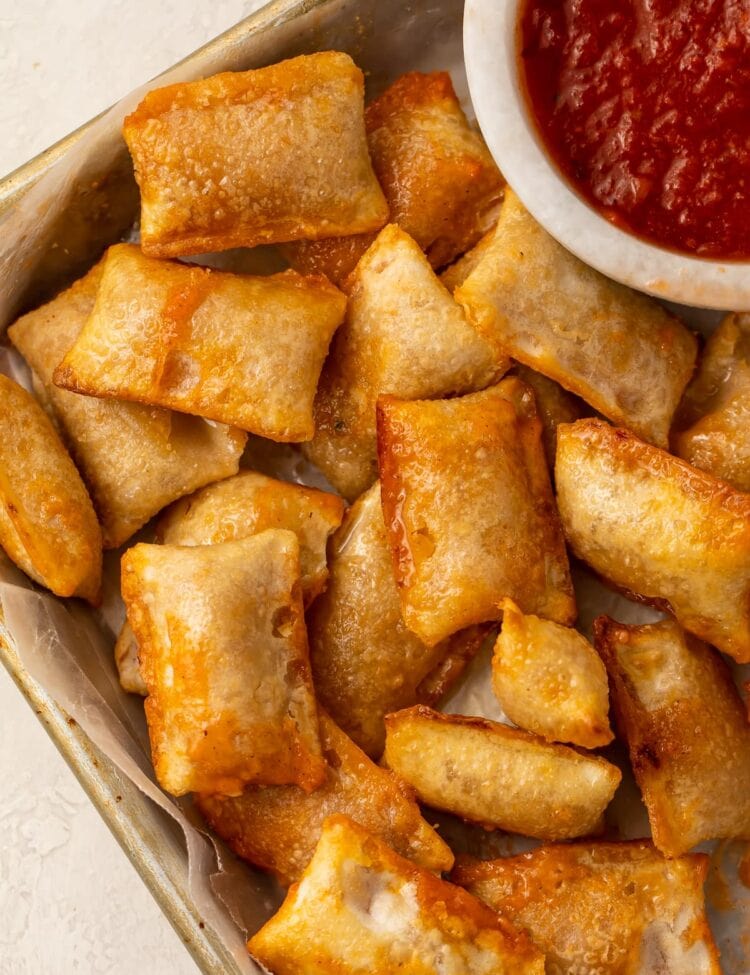 Pizza rolls cooked in the air fryer on a plate with a bowl of pizza sauce
