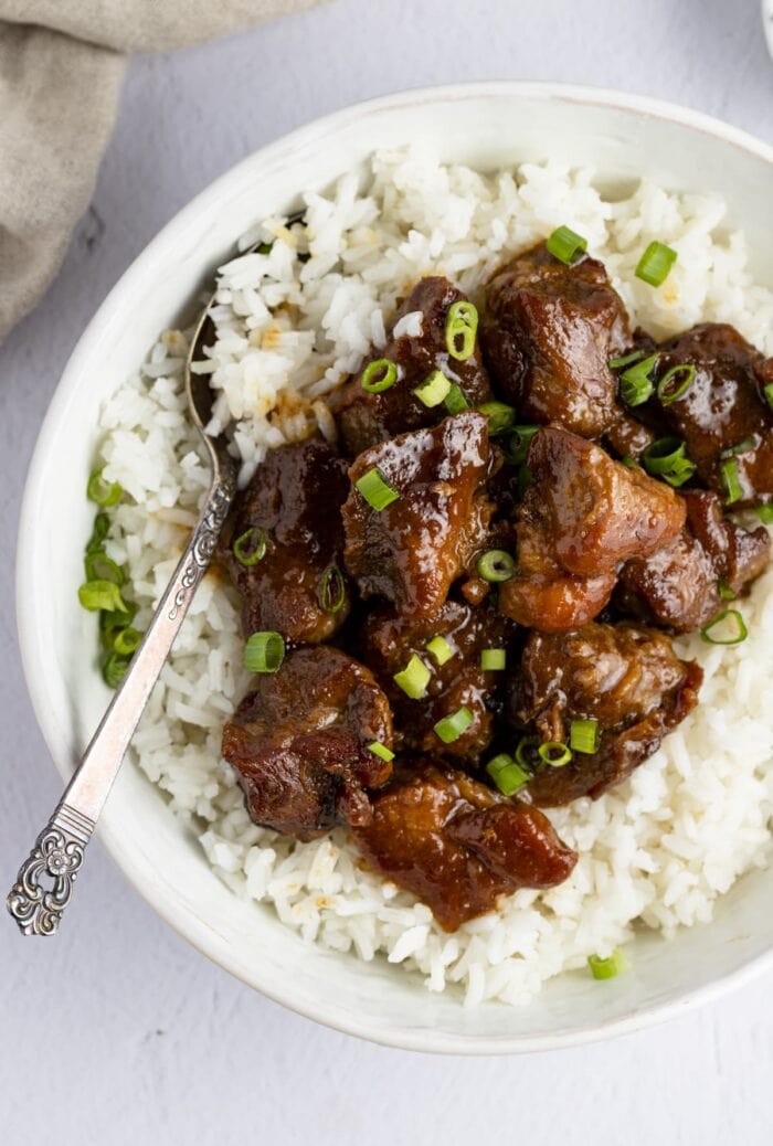 Pork adobo on top of white rice in a serving bowl