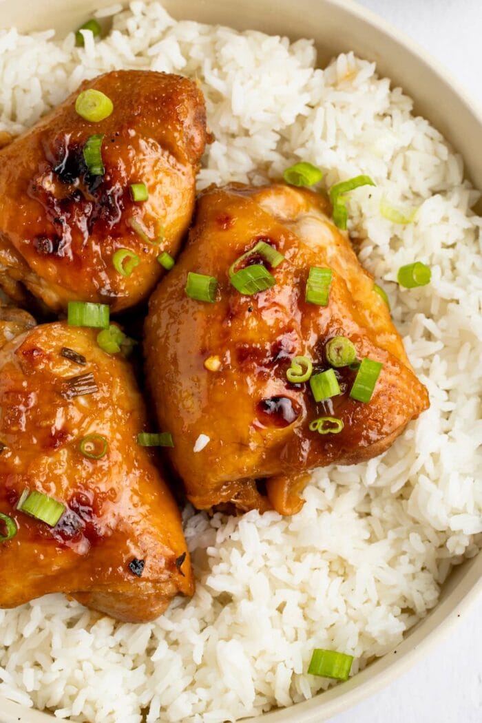 Overhead angle of shoyu chicken thighs on a bed of white rice, garnished with green onions