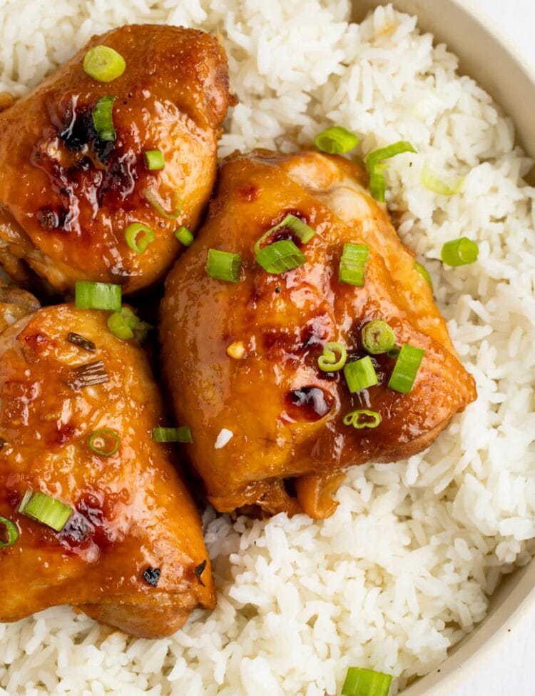 Overhead angle of shoyu chicken thighs on a bed of white rice, garnished with green onions