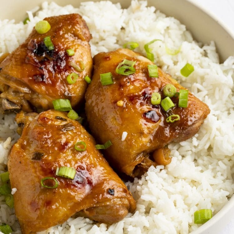 Shoyu chicken thighs on a bed of white rice, garnished with green onions