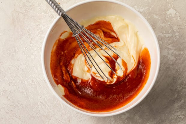 Sriracha and mayonnaise in small bowl with whisk