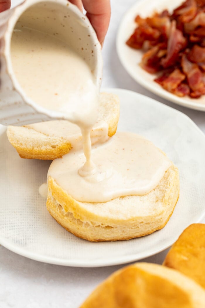 bacon gravy being poured over biscuits on a plate