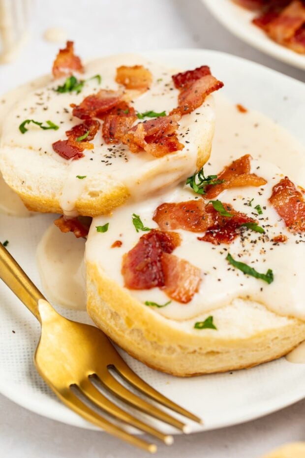 bacon gravy on biscuits with bacon pieces and chopped parsley on top