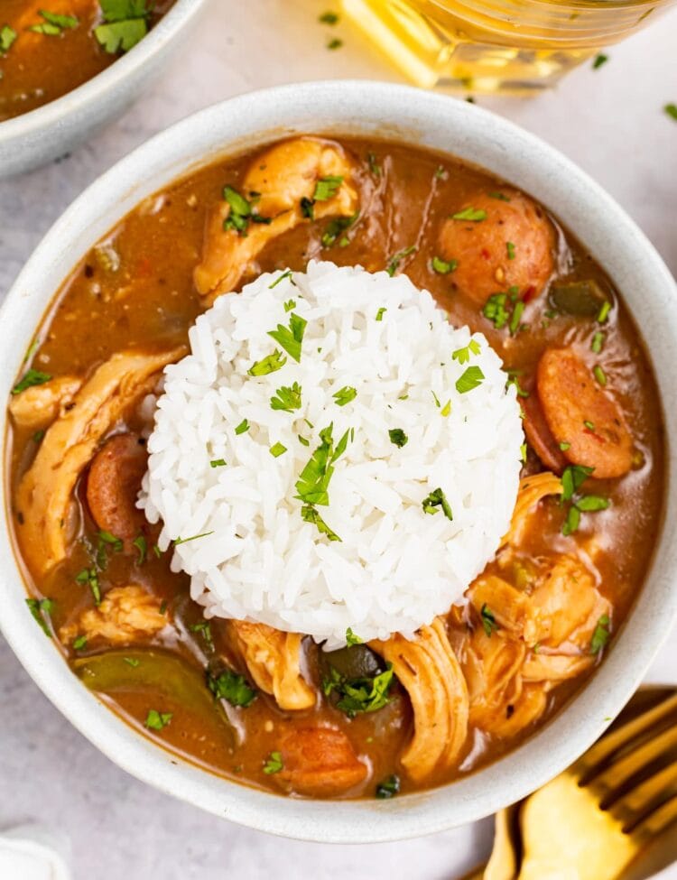 chicken and sausage gumbo in a bowl with a scoop or rice on top