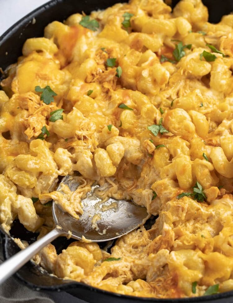 Buffalo chicken mac and cheese in a cast iron skillet with a spoon