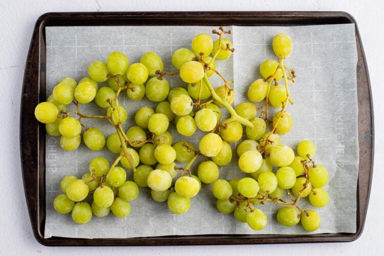 Green grapes on a baking sheet lined with parchment paper