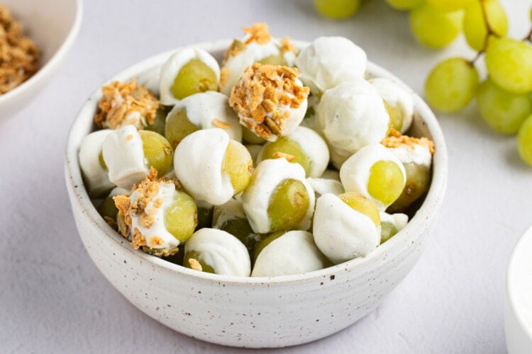 Frozen yogurt-covered grapes with granola in a bowl