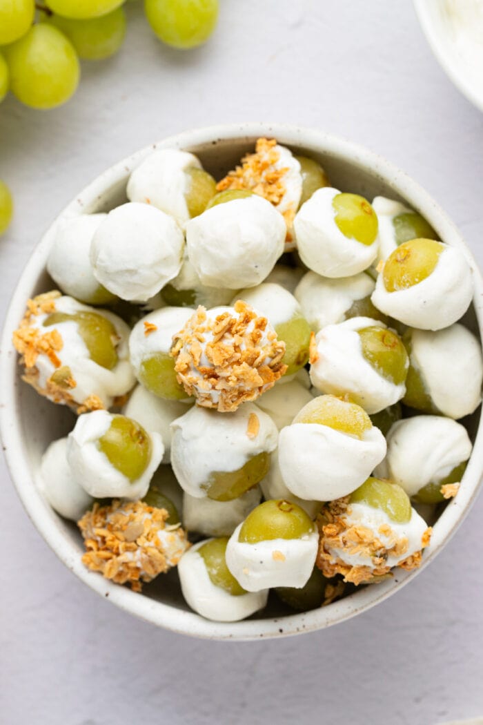 Overhead photo of frozen yogurt-covered grapes with granola in a bowl