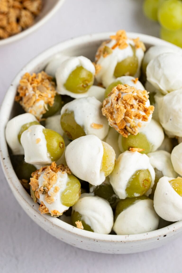 Frozen yogurt-covered grapes with granola in a bowl