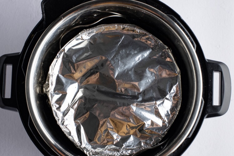 Springform pan covered with aluminum foil lowered into Instant Pot