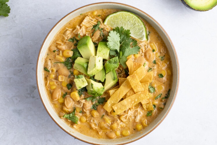 Instant Pot white chicken chili in a bowl with diced avocado, cilantro, and lime on top