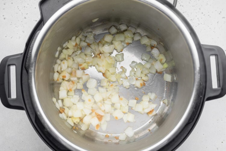 Diced onion and minced garlic in the bottom of an Instant Pot.