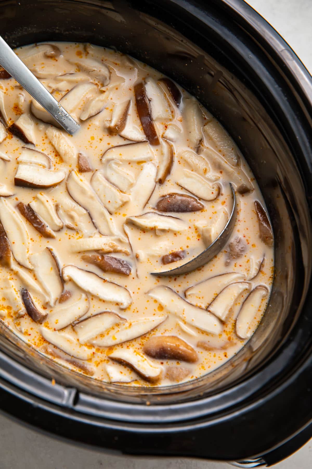 Crockpot Tom Kha Gai soup in a black slow cooker insert.