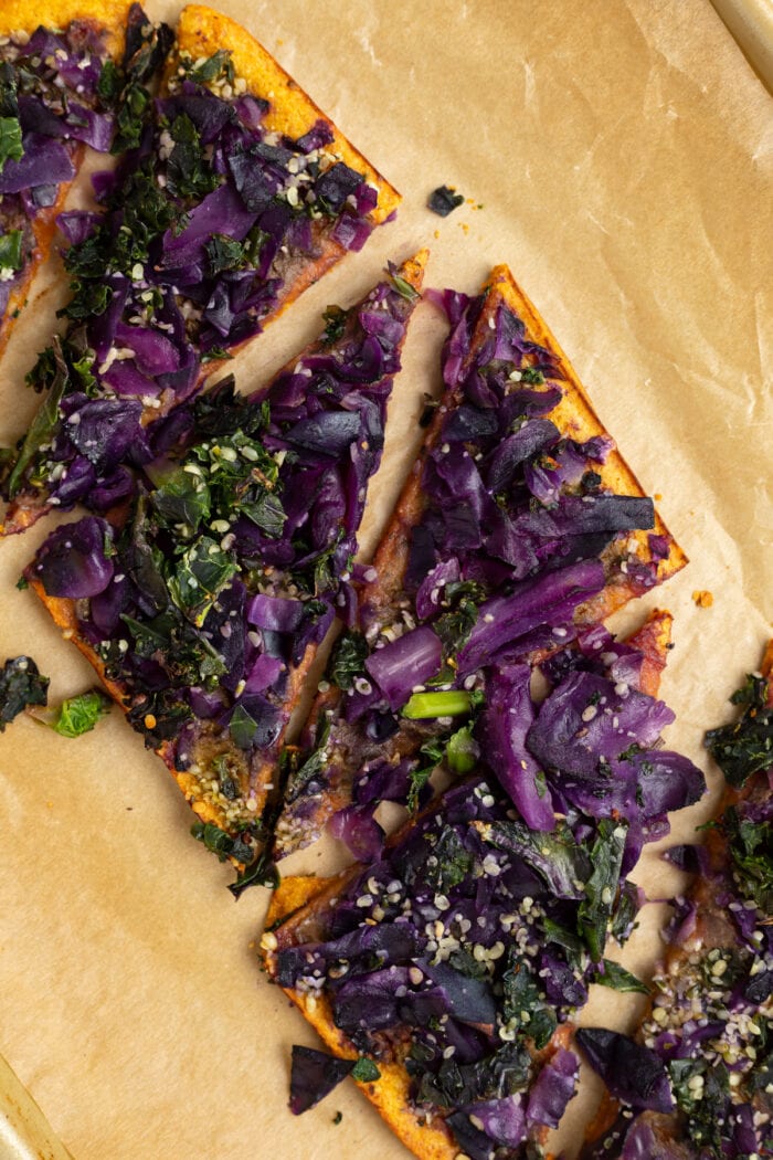 Daily Harvest sweet potato and kale flatbread, cooked and cut on a sheet of parchment paper