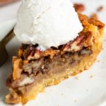 slice of keto pecan pie on a plate with sugar-free vanilla ice cream on top
