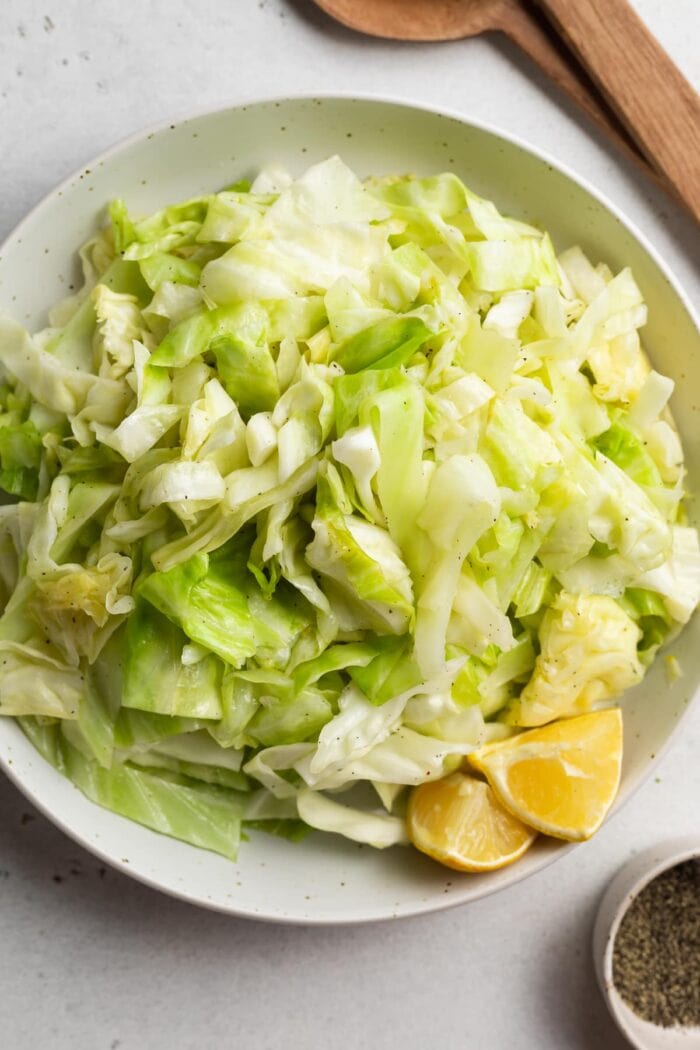 sauteed cabbage in a bowl with serving spoons on the side