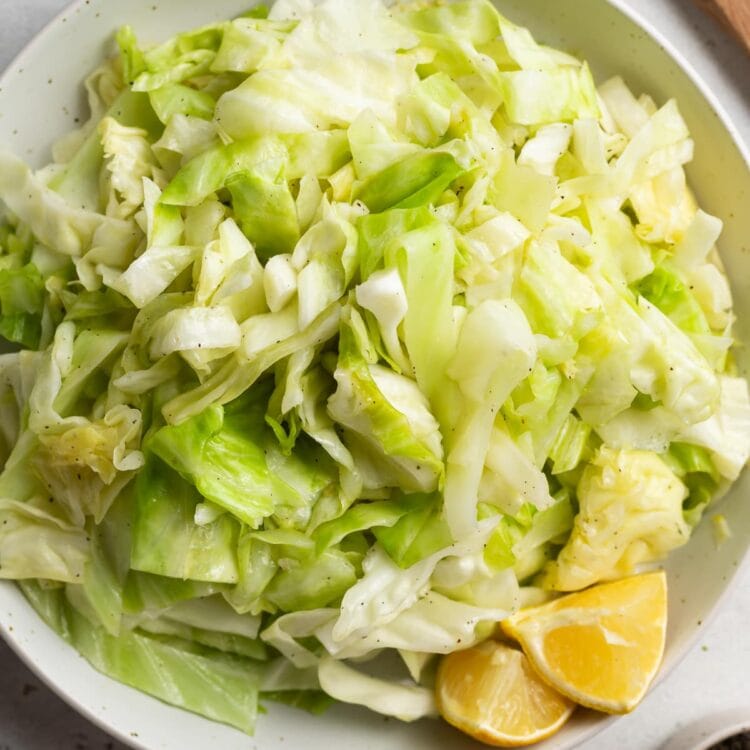 sauteed cabbage in a bowl with serving spoons on the side