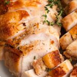 close-up image of sliced sous vide turkey breast with fresh thyme on top