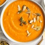 overhead image of sweet potato soup in a bowl with pumpkin seeds and fresh thyme on top
