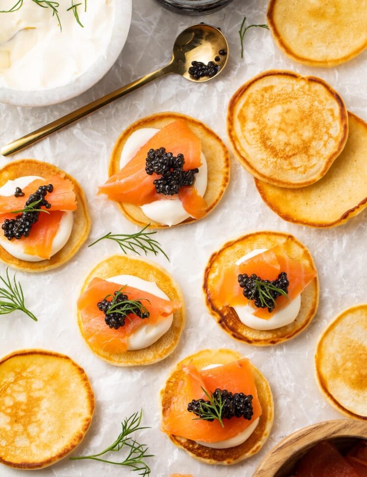 Blini, some topped with salmon and caviar, spread out on a table