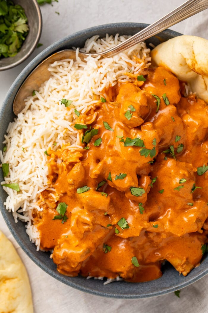 Instant Pot butter chicken, steamed basmati rice, and naan in a large black bowl